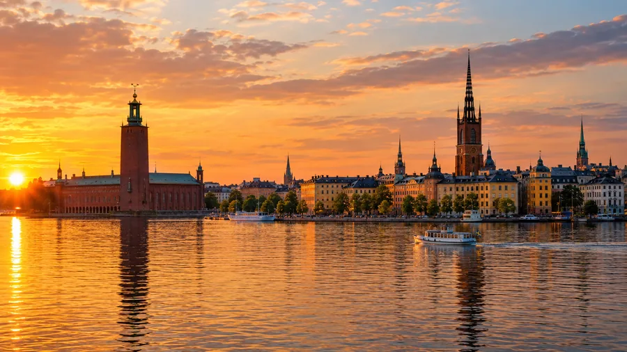 Stadshusetornet och Riddarholmskyrkans spira över lugna Mälaren i gyllene kvällsljus